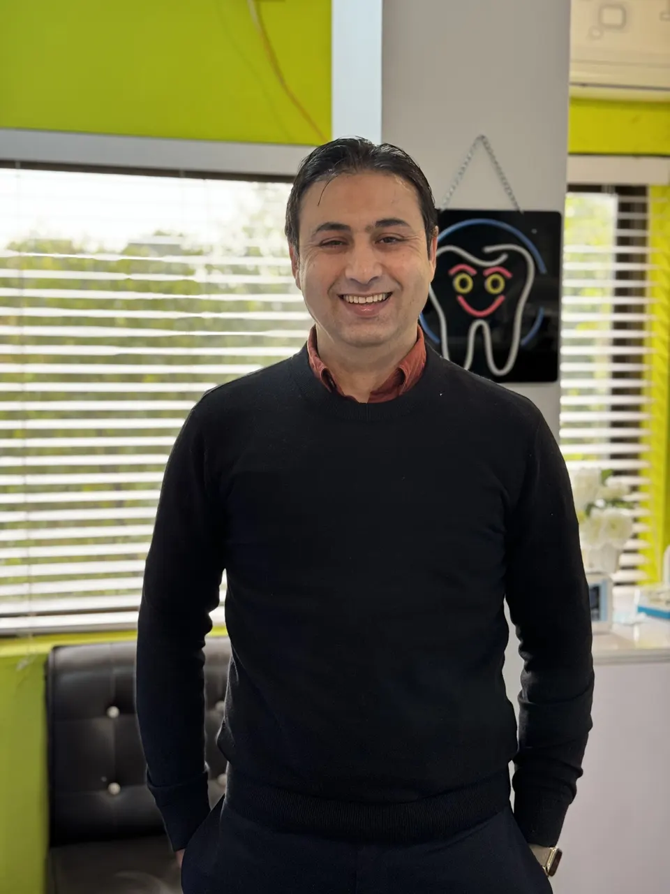 Assoc. Prof. Dr. Imran Khan Yusafzai, smiling, in a treatment room at the practice.