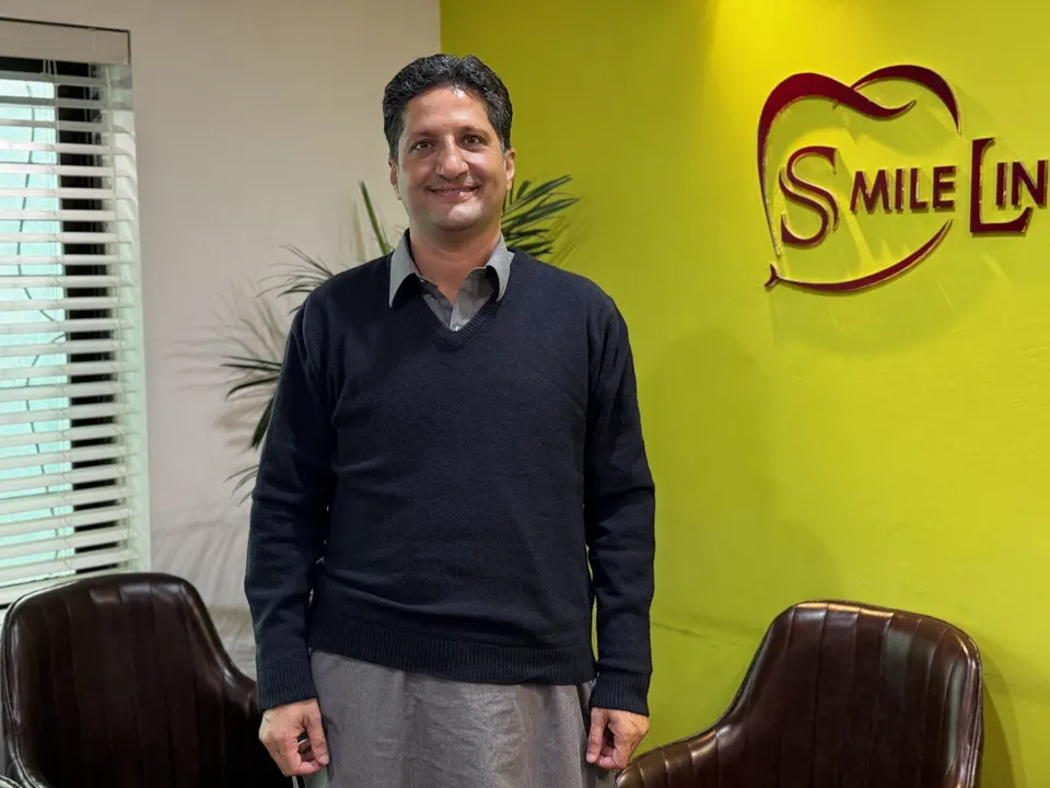 Assoc. Prof. Dr. Muhammad Jamal, standing in front of the Smile Line logo wall.