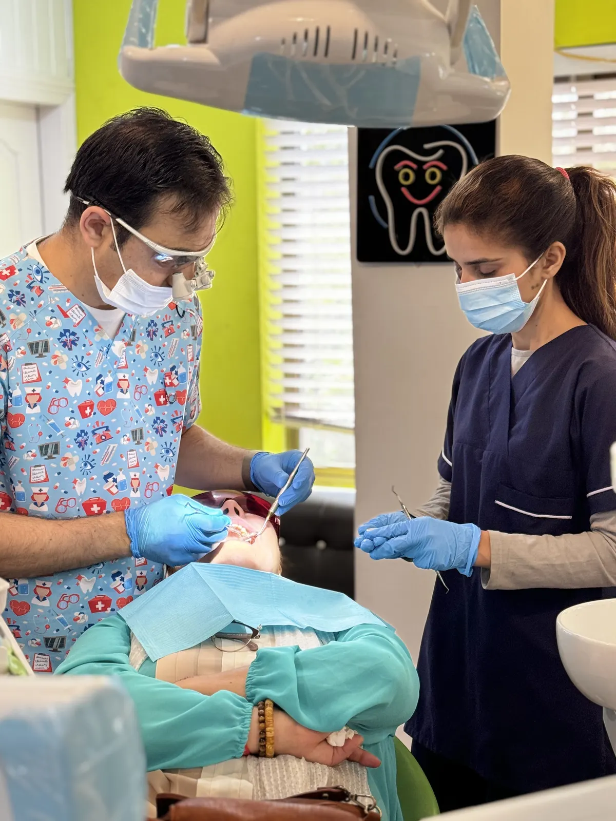 Dr. Imran Khan Yusafzai, wearing loupes, treating a patient with an assistant.